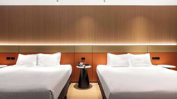 Quarto de hotel com duas camas, uma mesa pequena e um telefone fixado na parede.