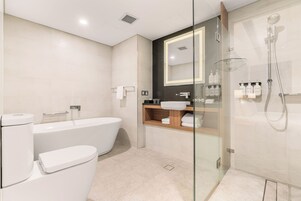 Un baño moderno con ducha de vidrio, bañera independiente y tocador con espejo.