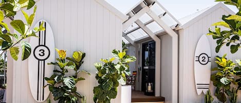 Un edificio moderno decorado con tablas de surf numeradas, rodeado de diversas plantas.