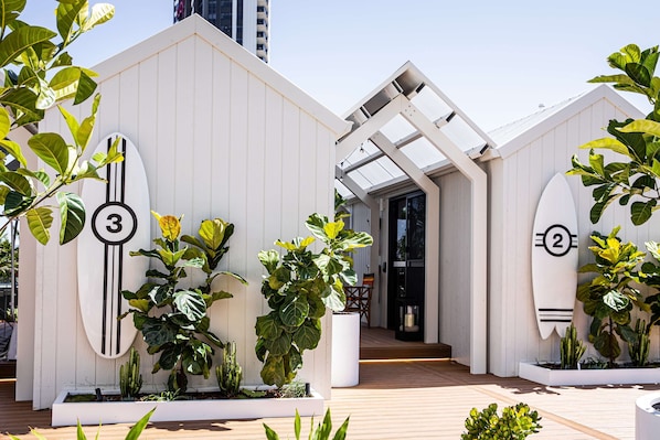 A modern building with numbered surfboards as decorations, surrounded by various plants. - QT Gold Coast (Surfers Paradise)