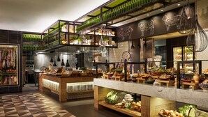 A restaurant with a modern interior, featuring a counter with various food items, shelves with bottles, and a decorative wall with animal illustrations.