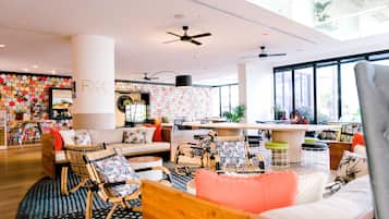 Un vestíbulo de hotel moderno con un área de estar central, un bar y un amplio ventanal con vistas al exterior.