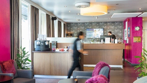 Un moderno vestíbulo de hotel con mostrador de recepción, zona de estar y grandes ventanales.
