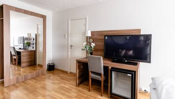 Ett modernt hotellrum med ett skrivbord i trä, en tv och en spegel.