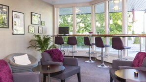 Ein moderner Lounge-Bereich mit bequemen Sitzmöglichkeiten, großen Fenstern und Kunstwerken an den Wänden.