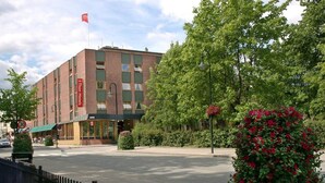Ein Hotel mit Backsteinfassade, großen Fenstern und einer Flagge auf dem Dach.
