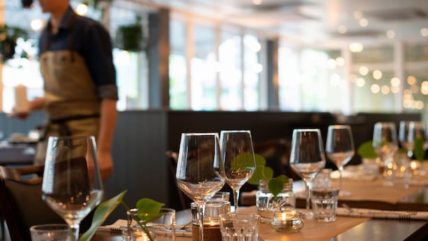 Ein Restaurantinnenraum mit gedeckten Tischen, klarem Glas und Kerzen.