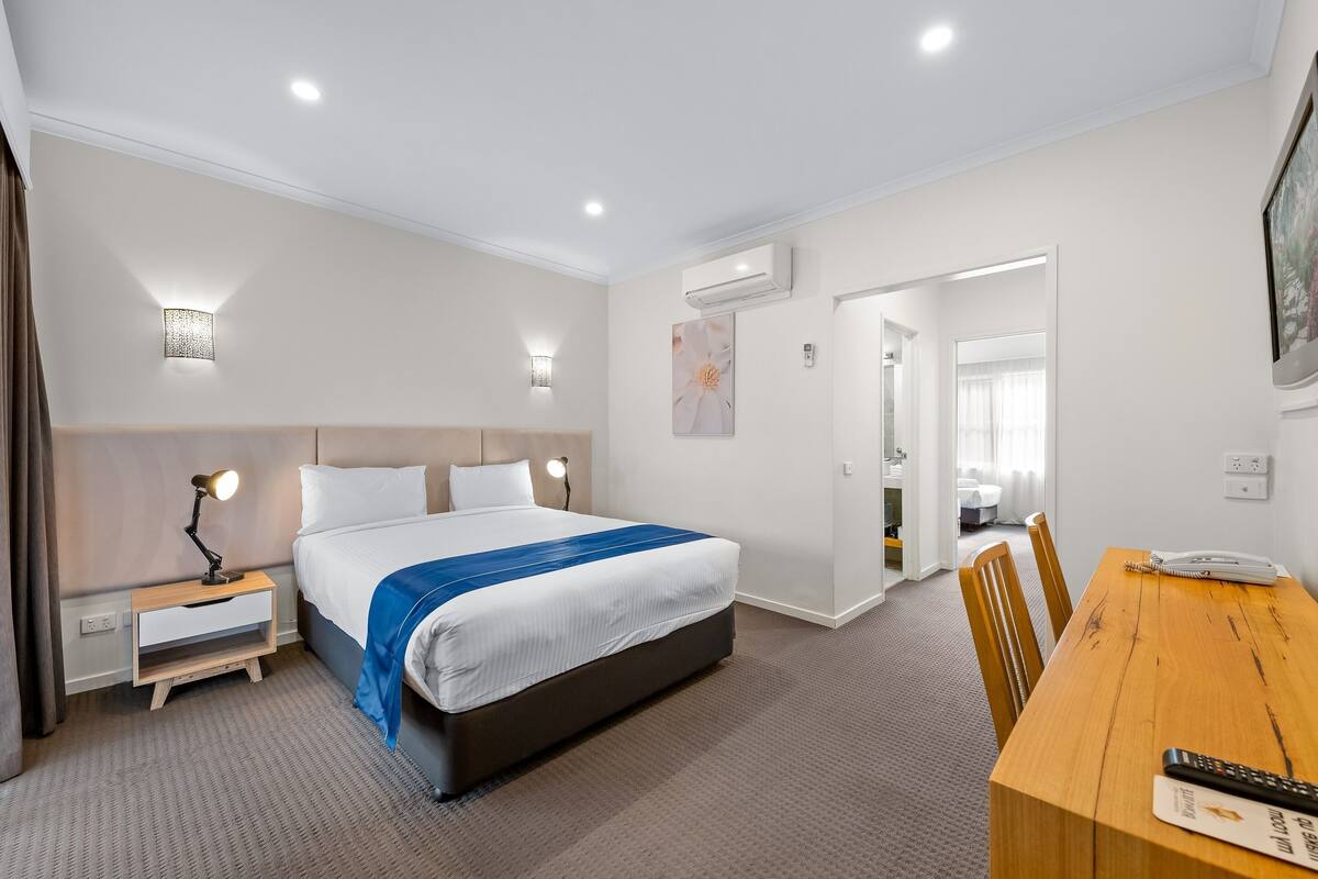 Una habitación de hotel con cama, mesitas de noche, un escritorio y una silla.