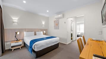 A hotel room with a bed, bedside tables, a desk, and a chair.