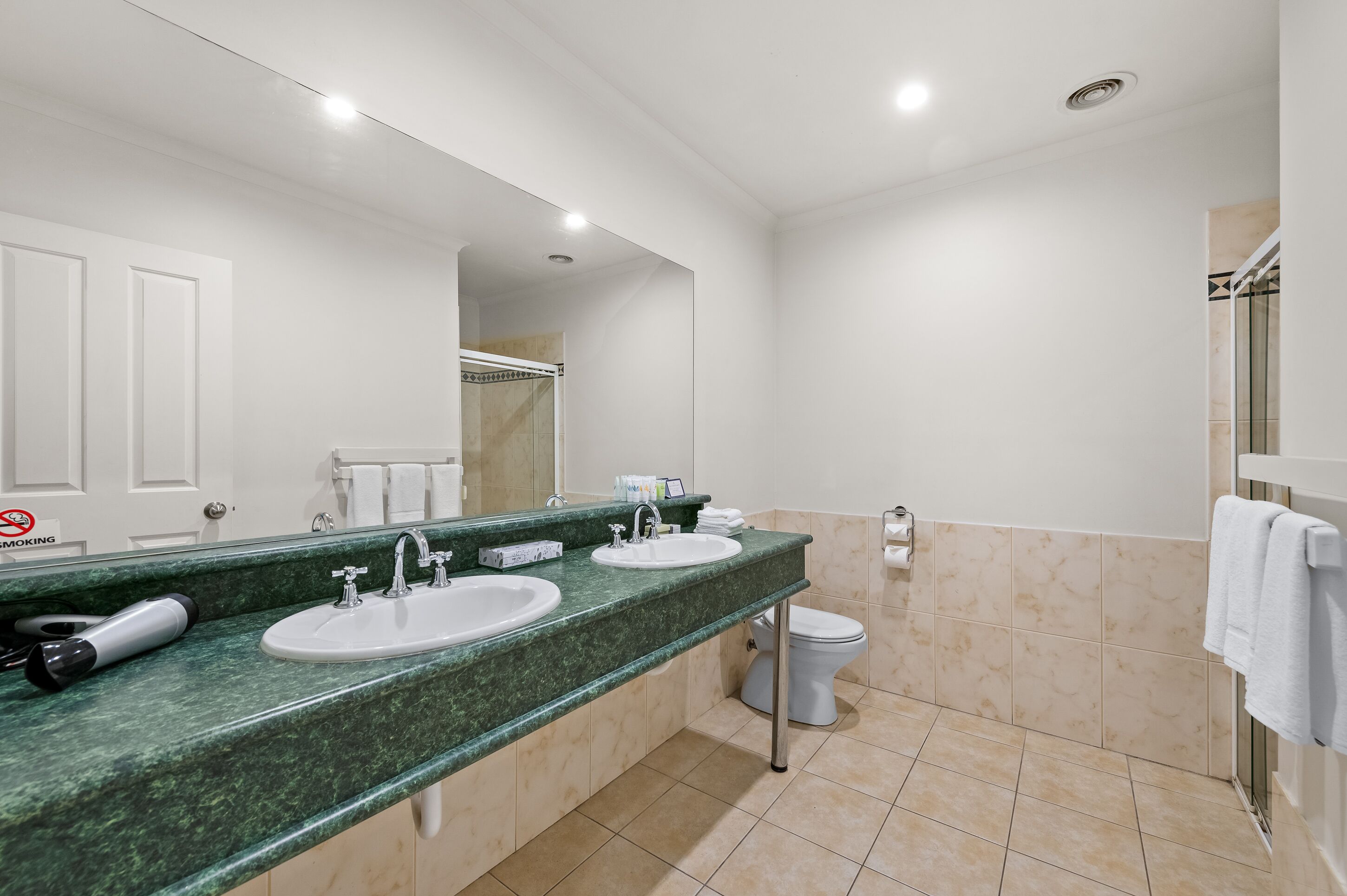 Une salle de bain avec deux lavabos, des toilettes et un espace douche.
