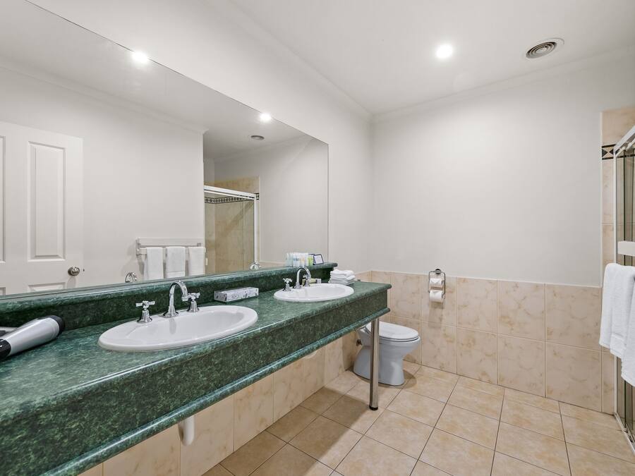 Un bagno con due lavandini, un WC e una zona doccia.