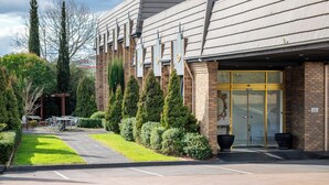 A building with a brick facade, a glass entrance, and a parking lot. - Rowville International Hotel (Rowville)