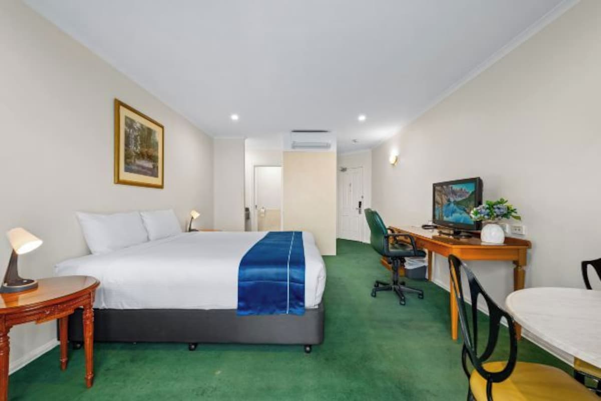 A hotel room with a bed, desk, chair, and a television.