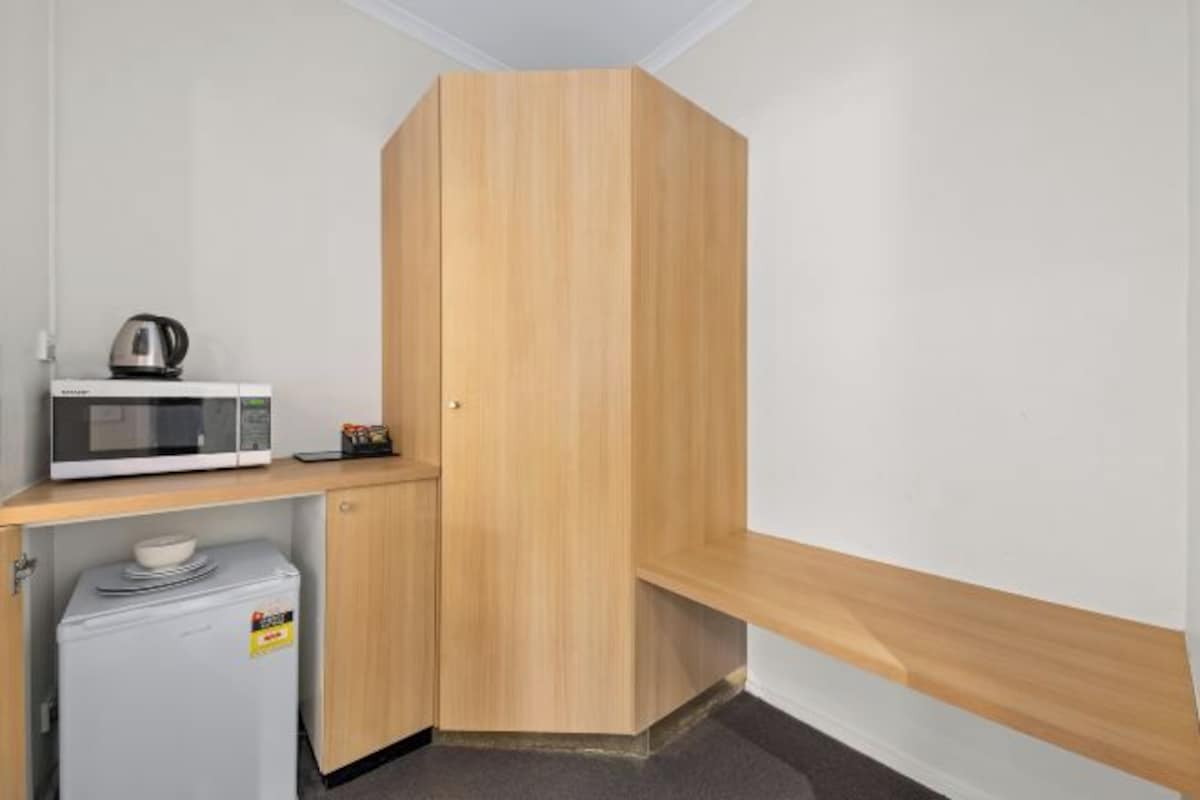 A compact kitchenette with a microwave, kettle, and small refrigerator.