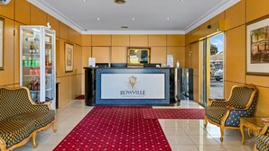 A reception area with a reception desk, a glass display case, and two ornate chairs. - Rowville International Hotel (Rowville)