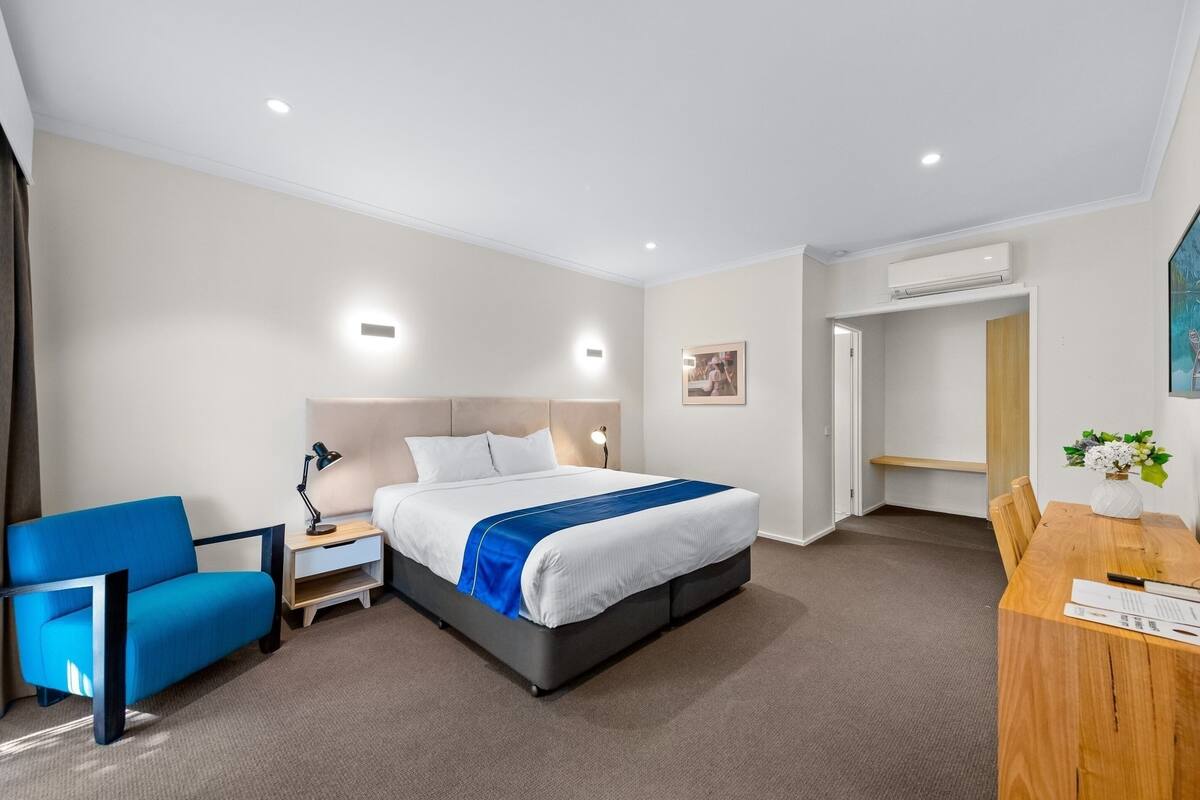 Habitación de hotel con cama, escritorio, silla y aire acondicionado.