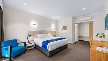 Habitación de hotel con cama, escritorio, silla y aire acondicionado.