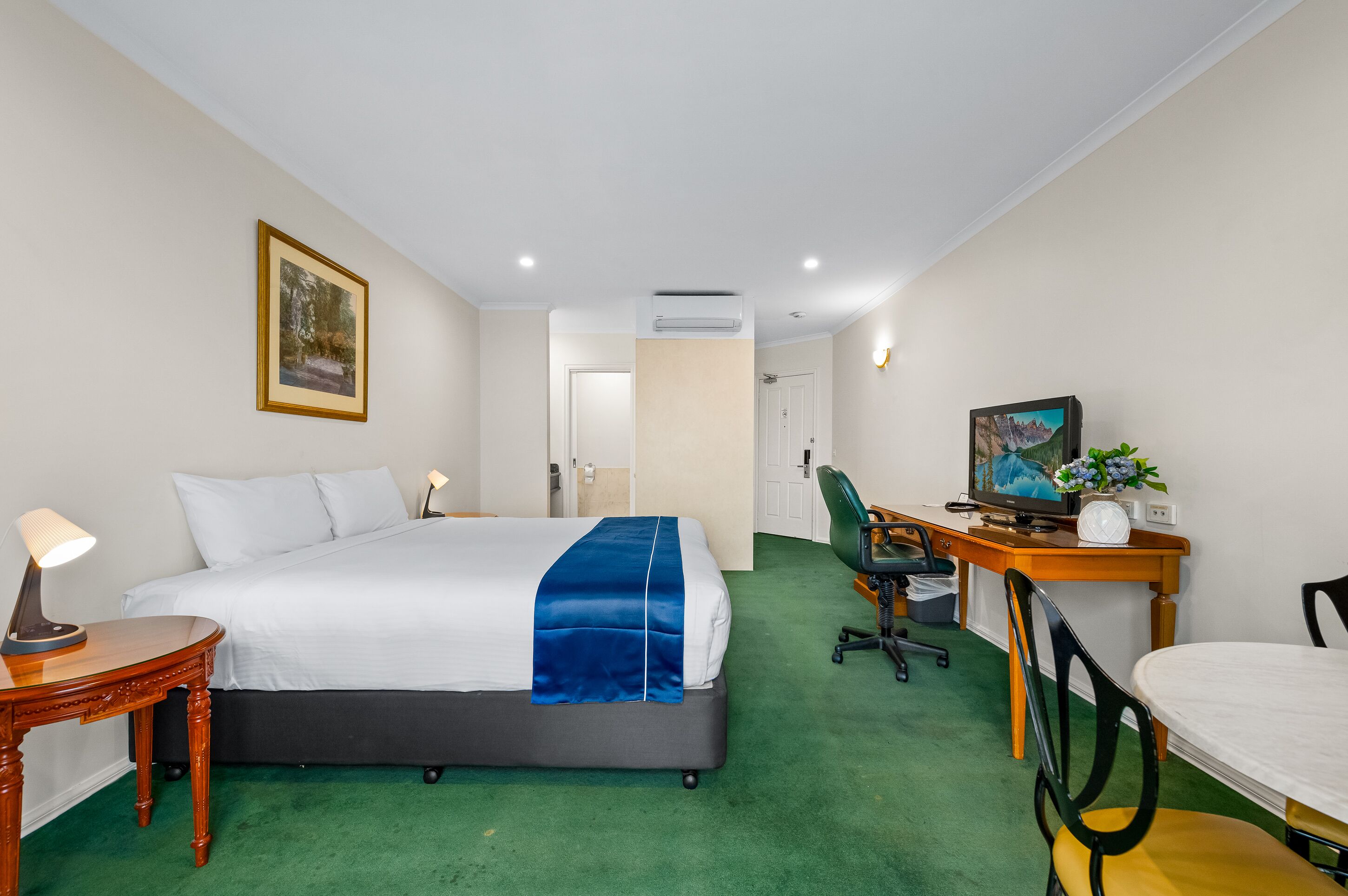 Habitación de hotel con cama, escritorio, silla y televisor.