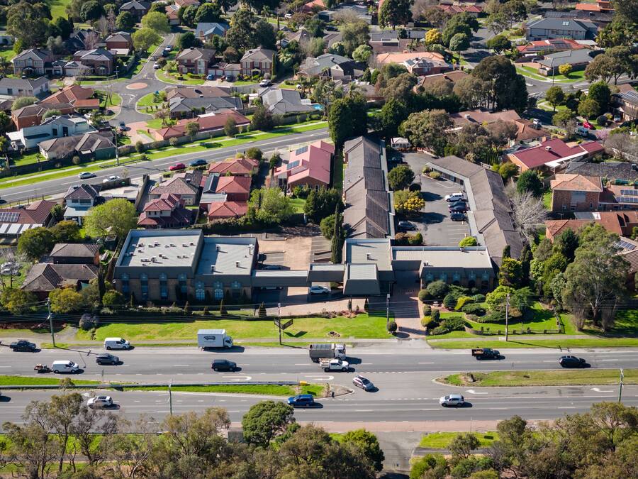 An aerial view of a residential area with houses, roads, and a large building with a flat roof.
