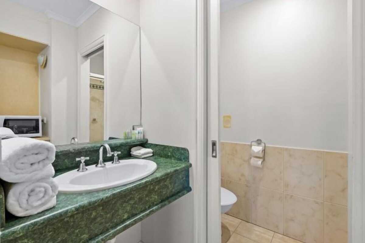 A bathroom with a green marble sink, white fixtures, and a toilet.