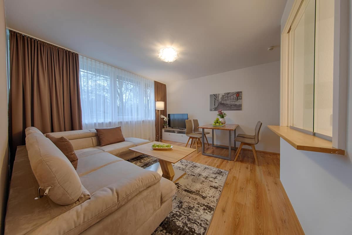 Ein modernes Wohnzimmer mit einem beige Coloured Sofa, einem Holztisch und einem Essbereich mit Tisch und Stühlen.