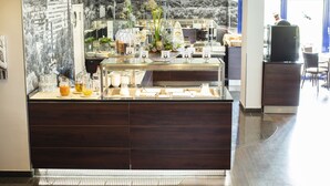 A breakfast bar with a variety of food and drink options, a decorative plant centerpiece, and a scenic mural in the background. - Best Western Hotel Wetzlar (Wetzlar)
