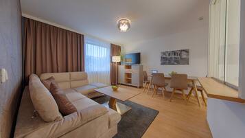 A modern living room with a sofa, coffee table, and dining area.