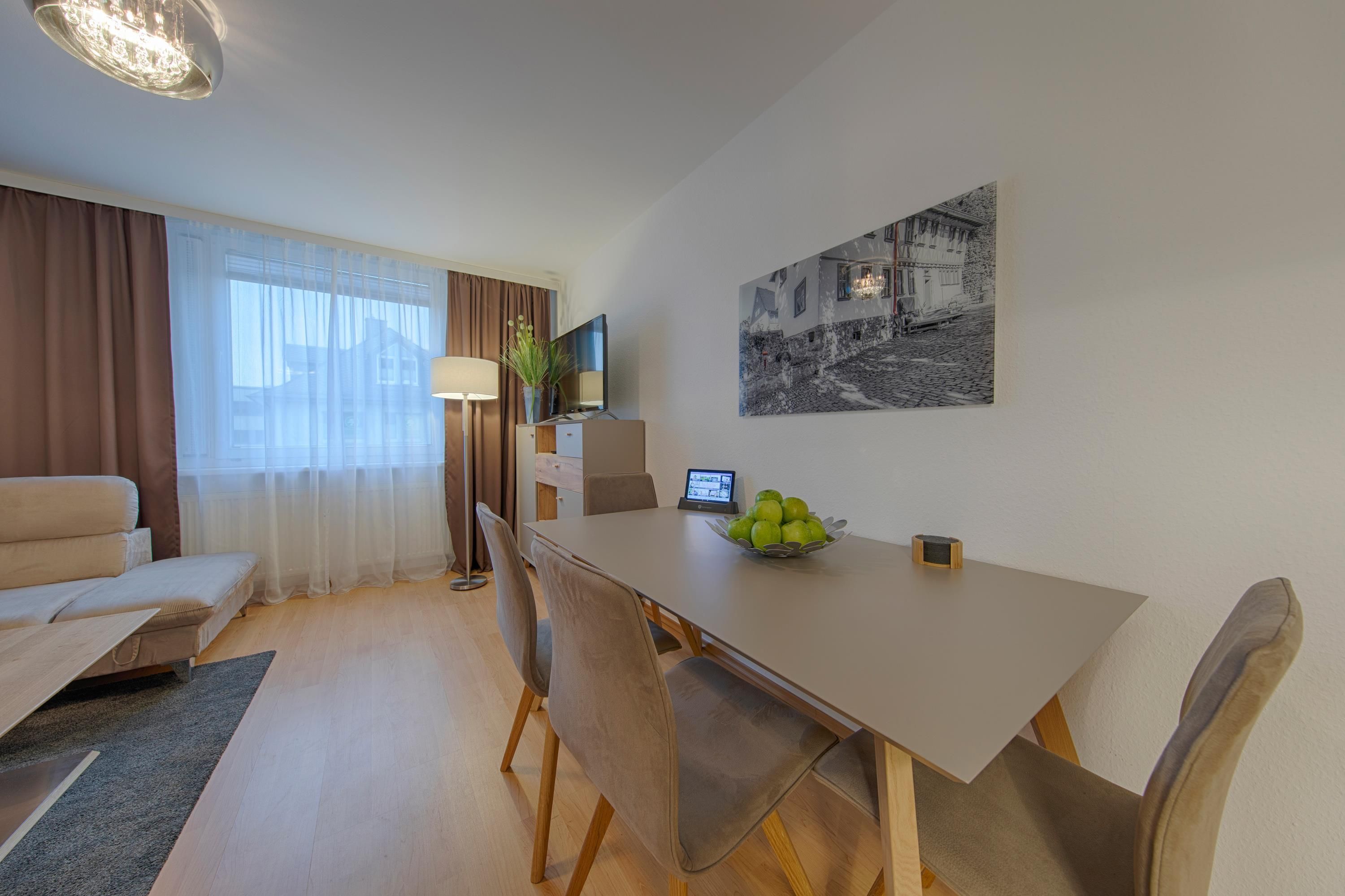 Une chambre d’hôtel moderne avec un coin repas, un canapé, une télévision et un tableau au mur.