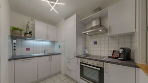 A modern kitchen with white cabinets, a built-in oven, and a coffee maker on the countertop. - Best Western Hotel Wetzlar (Wetzlar)
