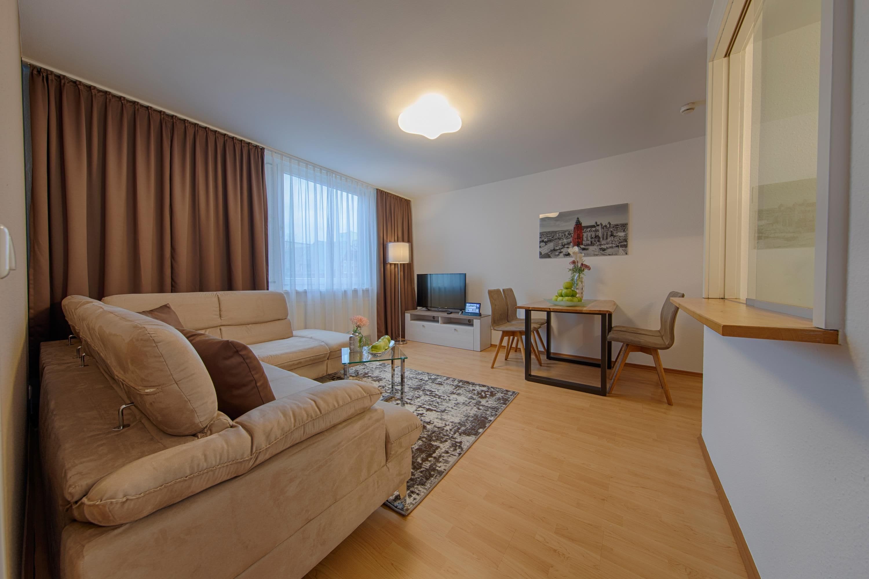 Een moderne woonkamer met een bank, een televisie, een eettafel en een stoel.