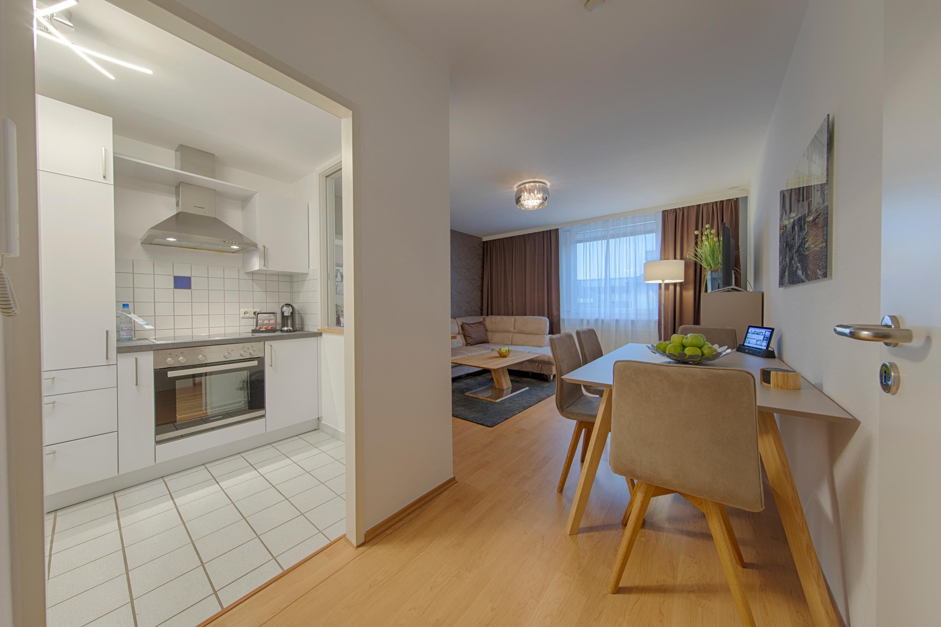 Una cocina moderna con horno empotrado y comedor con mesa y sillas.