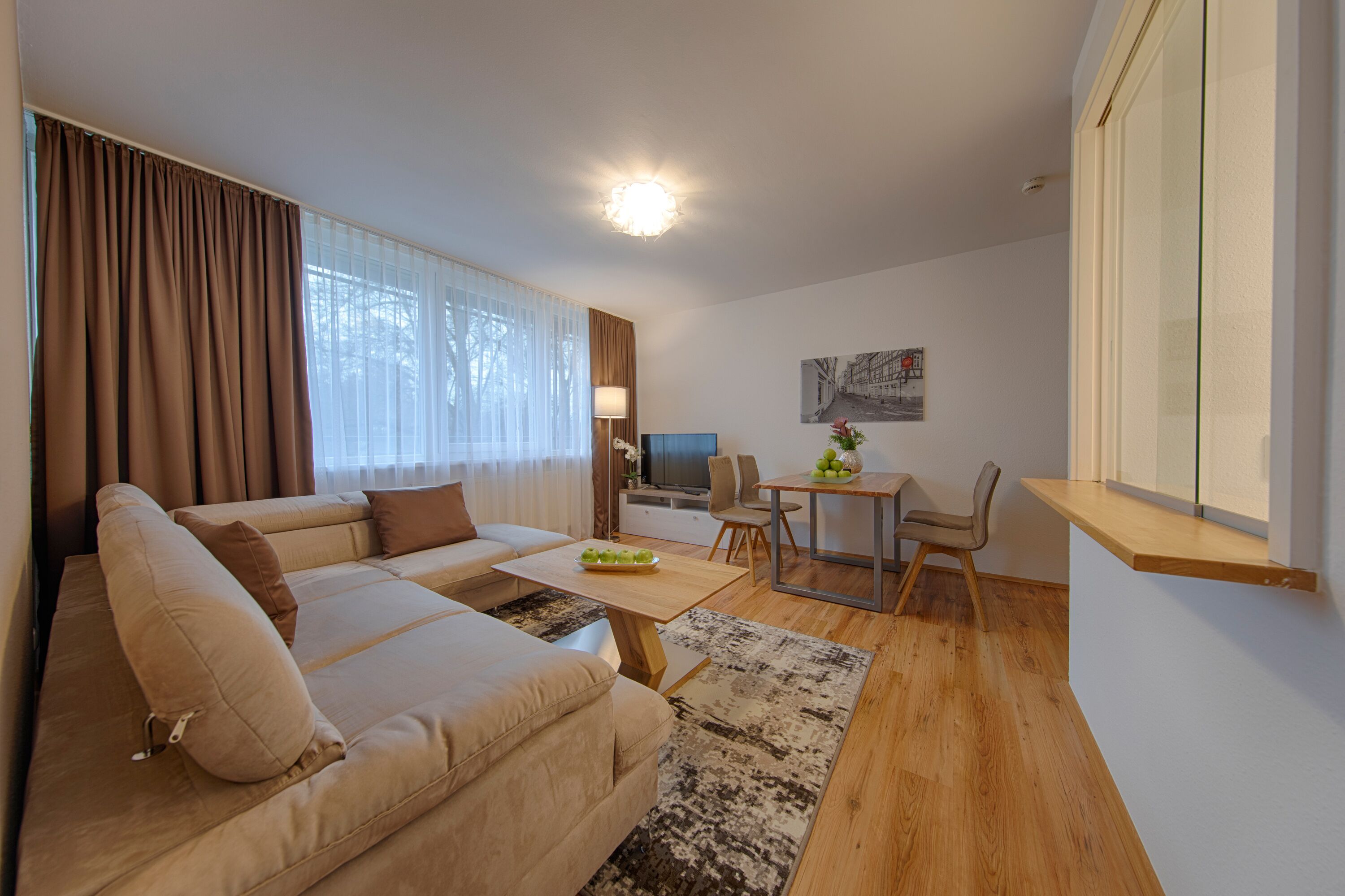 A modern living room with a sofa, a dining table, and a TV.
