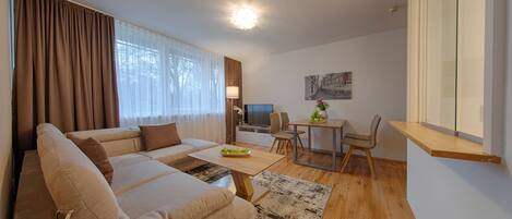 A modern living room with a sofa, a dining table, and a TV.