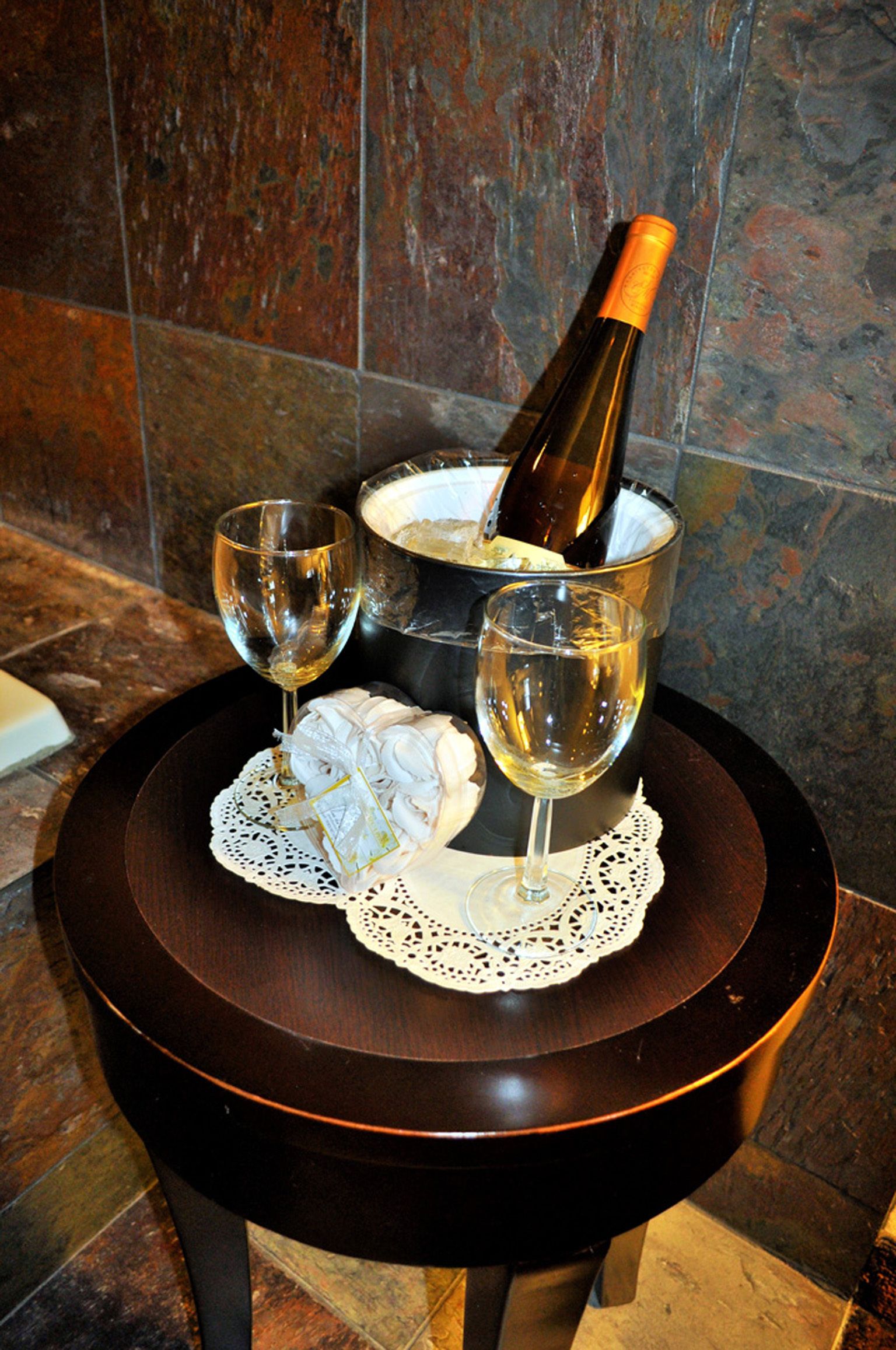 A table with a bottle of champagne, two glasses, and a decorative item on a doily.
