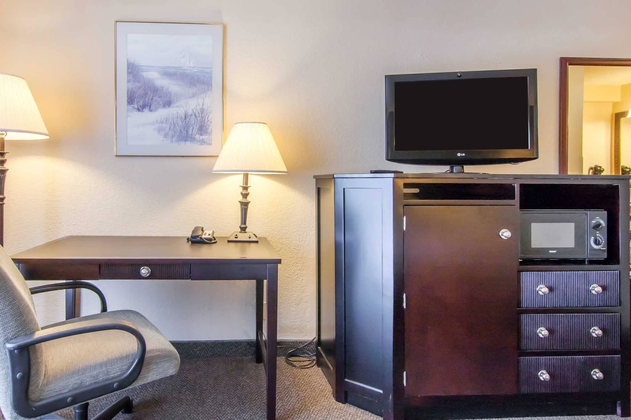 Camera d'albergo con scrivania, sedia, televisore e minibar.