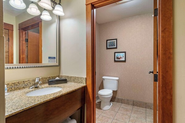 A bathroom with a granite countertop sink, a mirror, and a toilet. - Comfort Inn & Suites Lincoln City (Lincoln City)