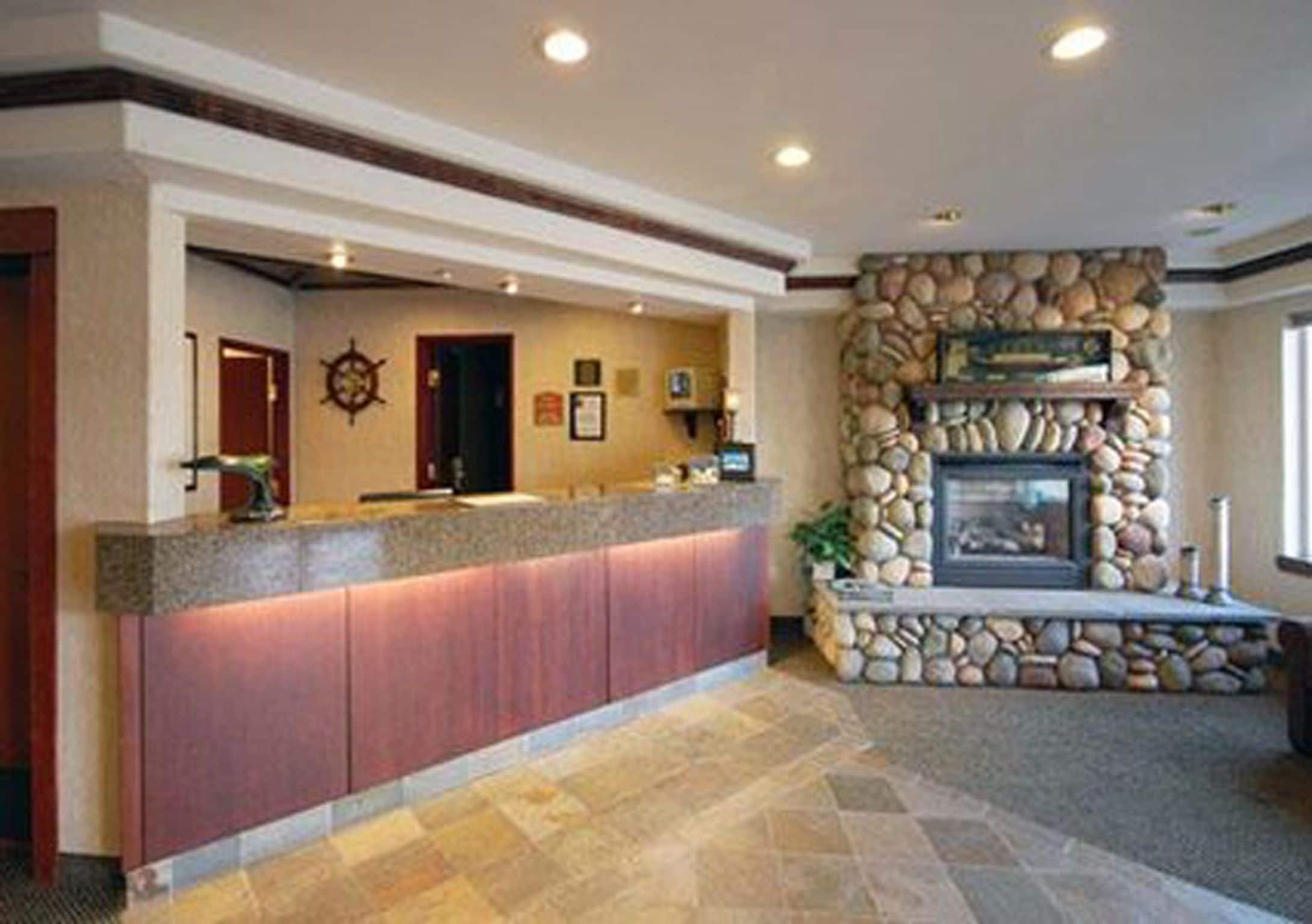 A reception area with a stone fireplace, a counter with a red panel, and a compass wall decoration.