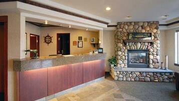 A reception area with a stone fireplace, a counter with a red panel, and a compass wall decoration.