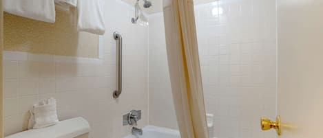 A bathroom with a toilet, bathtub, and shower.