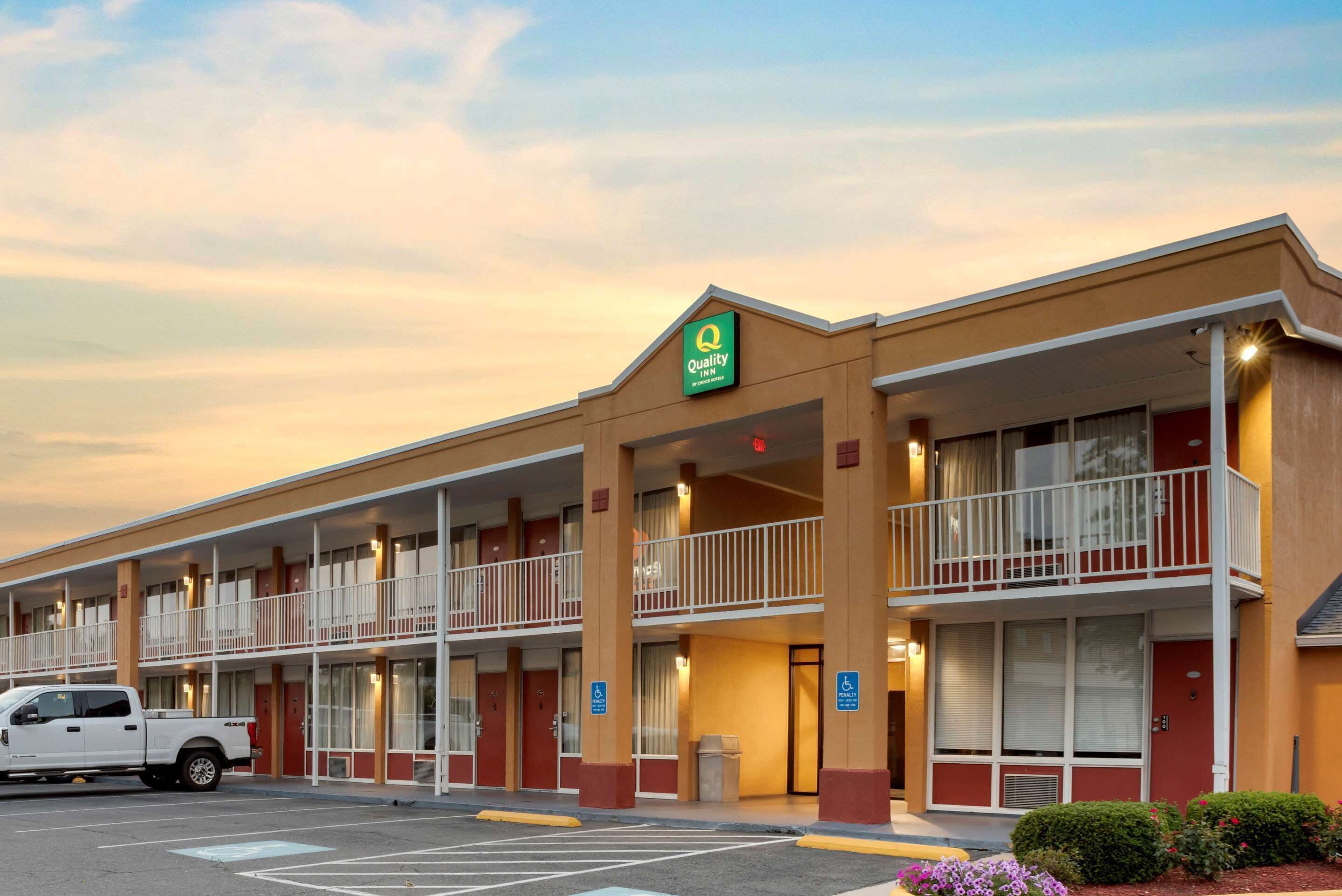 Un motel con diversi balconi, un parcheggio e un cartello che indica che si tratta di un Quality Inn.