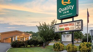 A Quality Inn by Choice Hotels sign with a New York Grill and pizza subs sign below it.