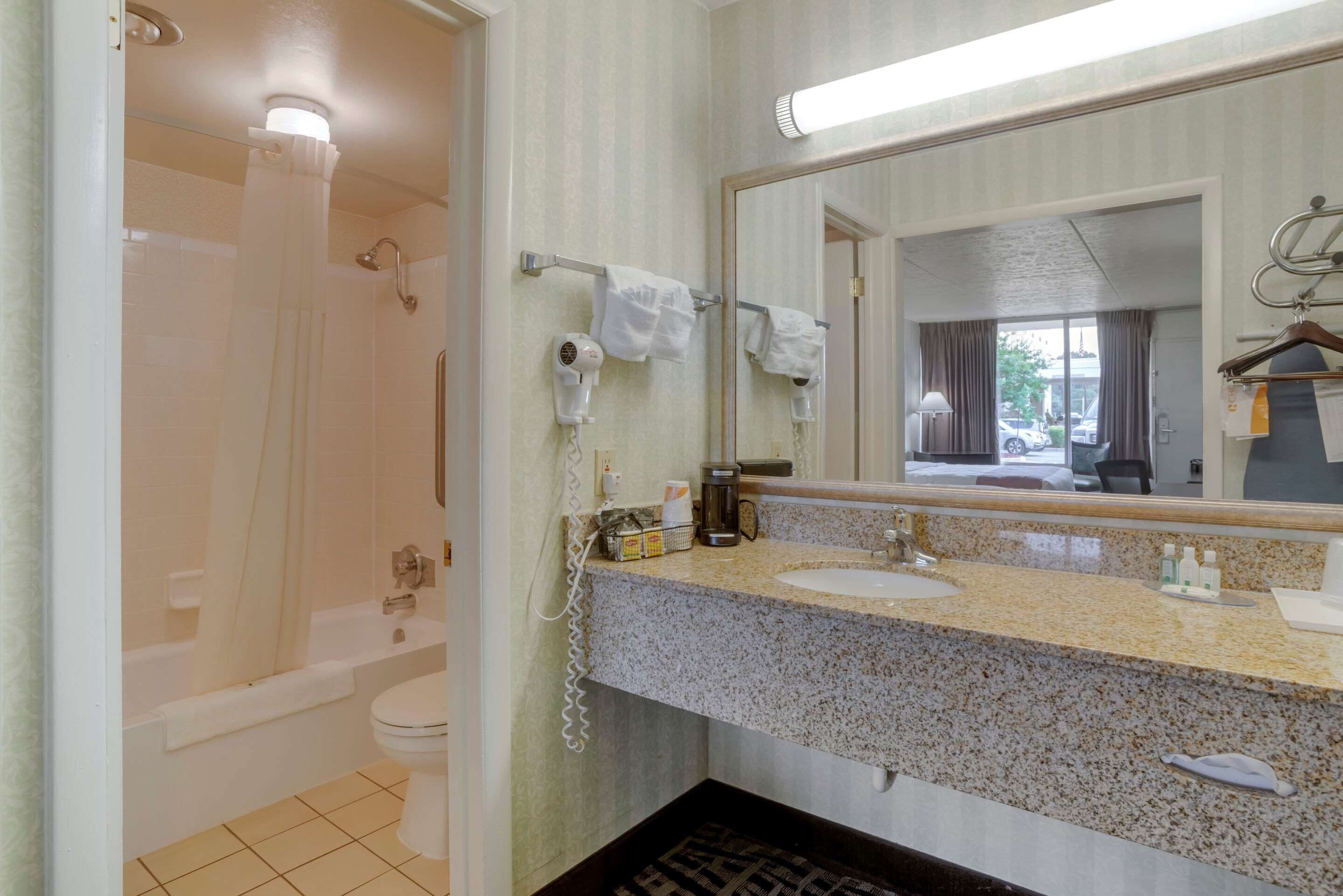 A bathroom with a bathtub, toilet, sink, and a mirror.