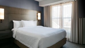 Ett hotellrum med en stor säng, två sängbord och ett fönster med gardiner.