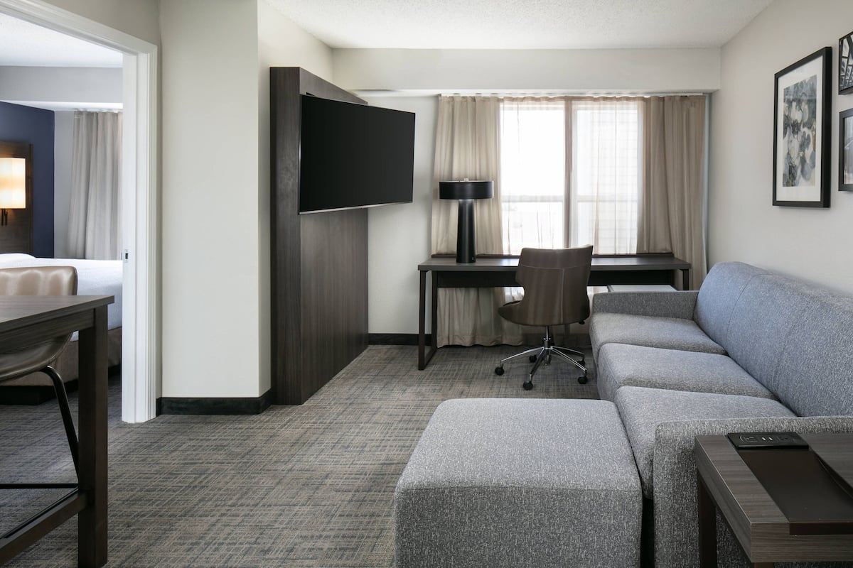 A hotel room with a bed, a desk, a TV, a sofa, and a chair.
