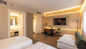 A hotel room with two beds, a desk, a chair, a TV, and a small table with a plant. - Intercity Pamplona - The Universe Paulista (São Paulo)