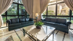 A modern living room with two black leather sofas, a glass coffee table, and a potted plant. - Intercity Pamplona - The Universe Paulista (São Paulo)