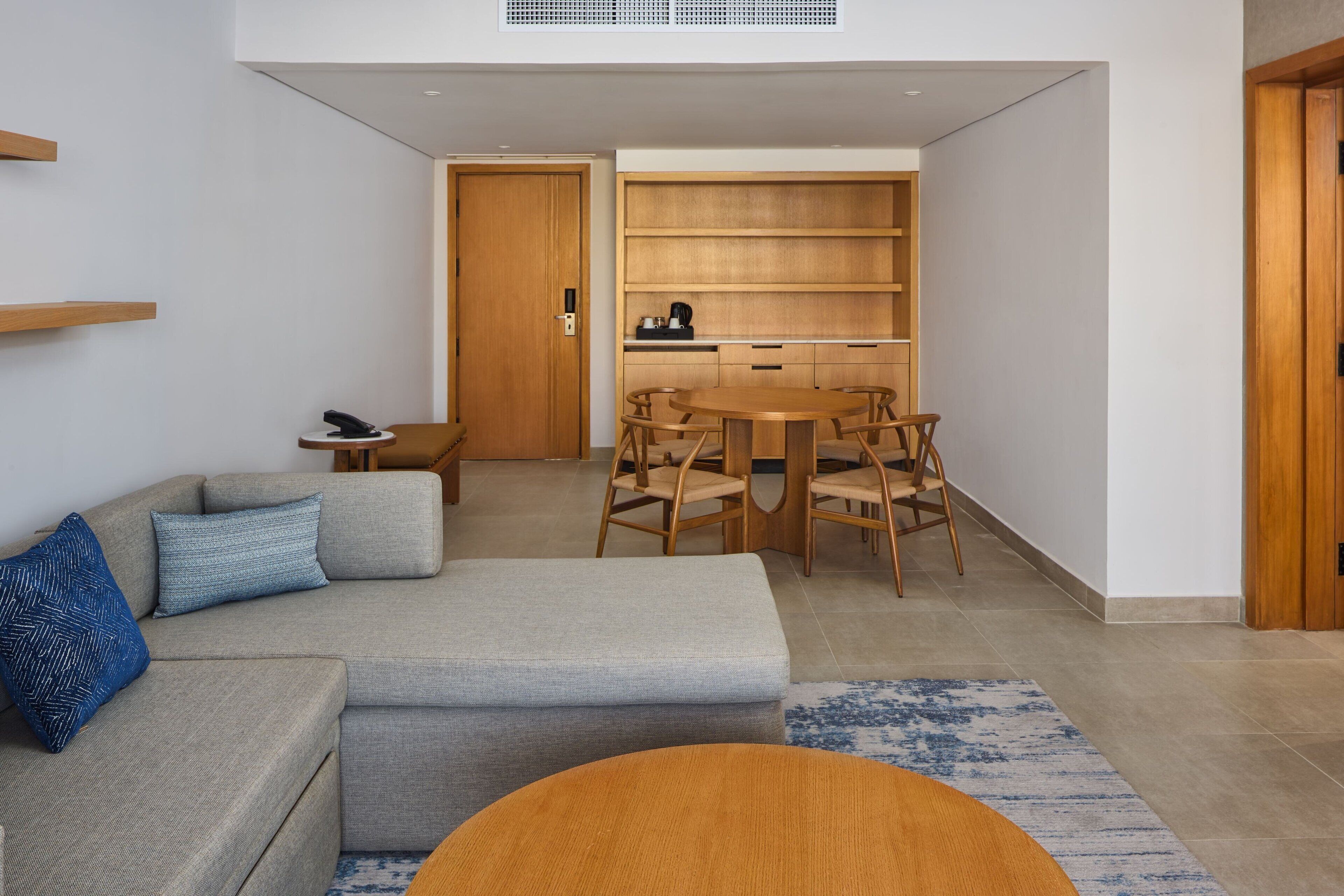 Una sala de estar moderna con un sofá, una mesa de centro y un comedor con sillas y un aparador de madera.