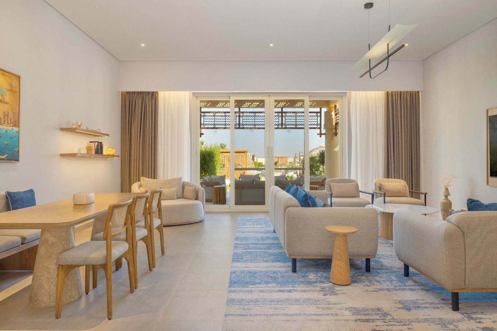 Ein modernes Wohnzimmer mit Essbereich, großen Fenstern und Blick ins Freie.