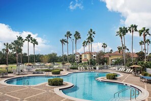 Una piscina al aire libre, sombrillas, sillones reclinables de piscina