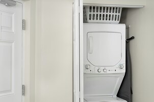 Un lavadero blanco con lavadora de carga frontal, un tendedero y una puerta.